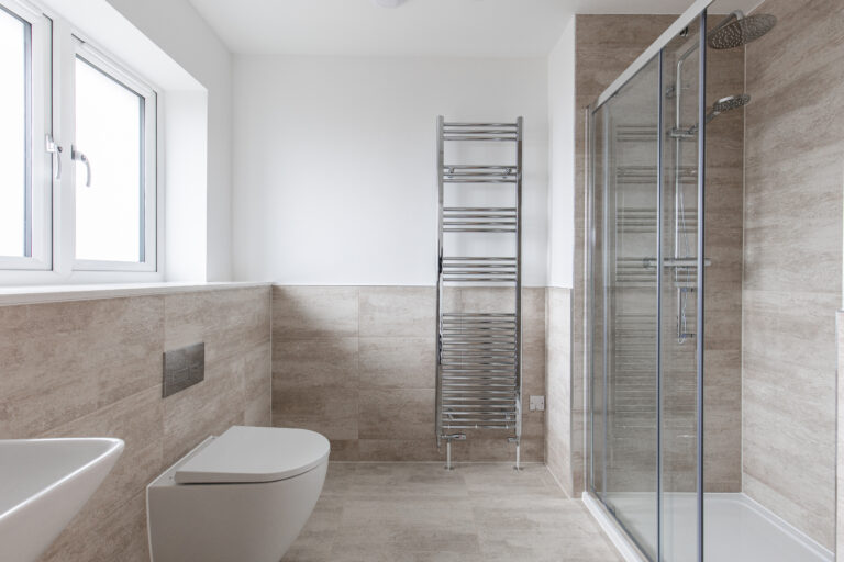 Ensuite with half height tiling, full height towel rail, double shower cubical with glass shower screen and chrome fittings.