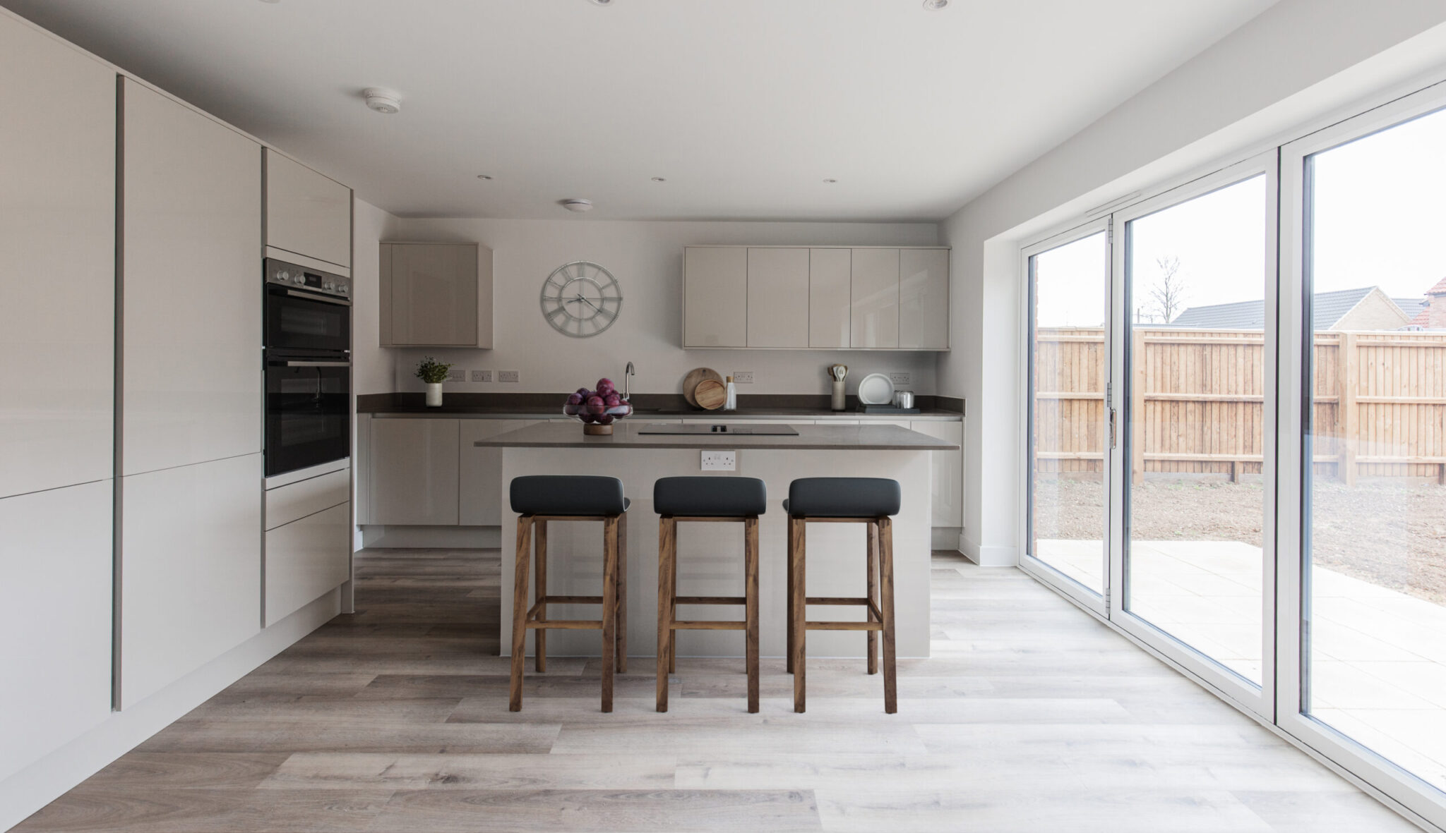 Gloss kitchen with breakfast area and large bifolding doors emitting natural light that lead to a south facing garden.