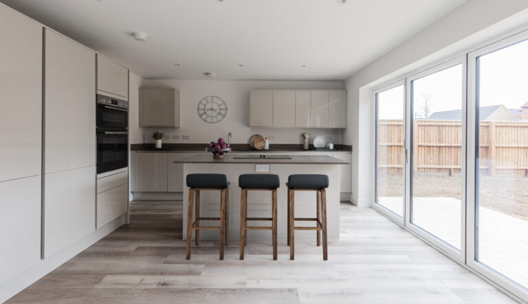 Gloss kitchen with breakfast area and large bifolding doors emitting natural light that lead to a south facing garden.