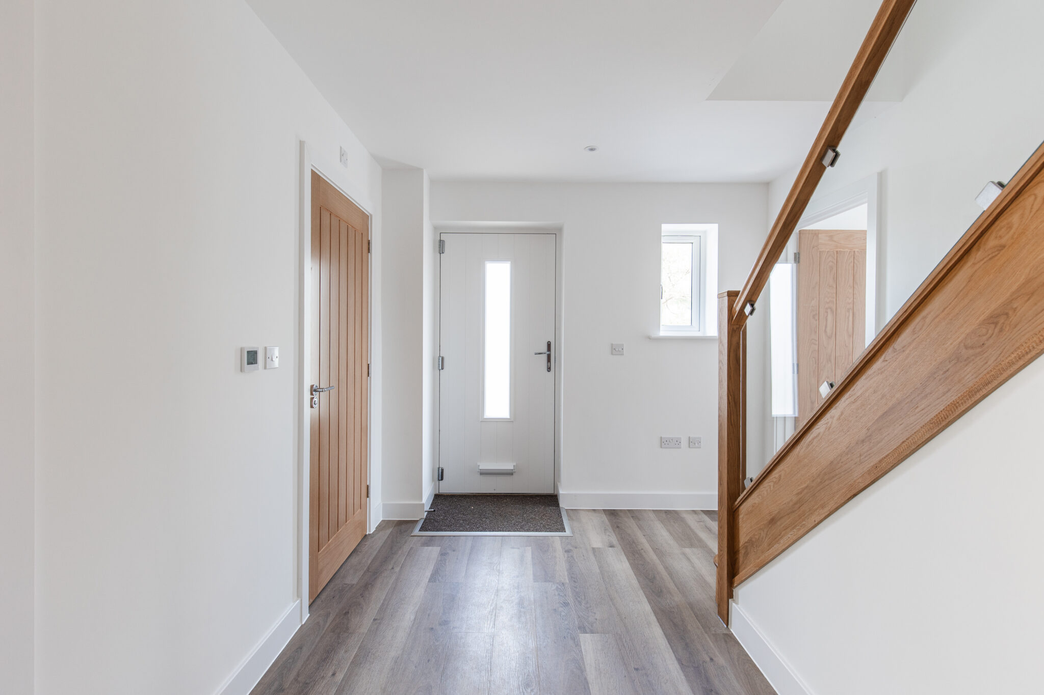 Hallway of 4 bedroom property with solid oak and glass staircase.