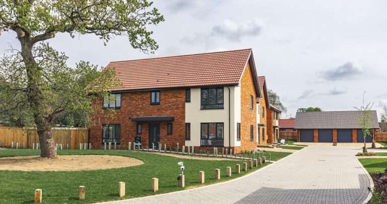 External view of a 4 bedroom detached home with green open space and road leading into new build development.